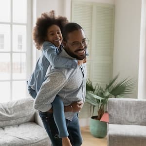 Father piggyback riding his daughter in the living room
