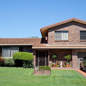 A brown brick house with a landscaped garden