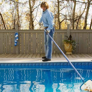 Man cleans fall leaves from pool
