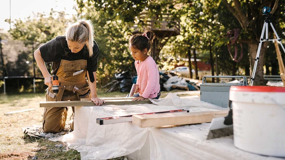 Mother and daughter working on construction project in backyard