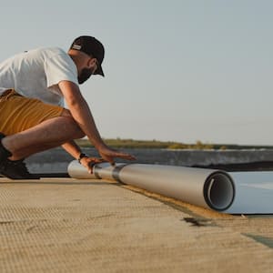 Worker installing pvc membrane roller on roof