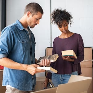 Couple packing books in cardboard boxes