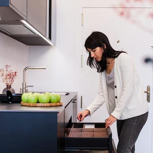 Woman sorts through drawer in kitchen