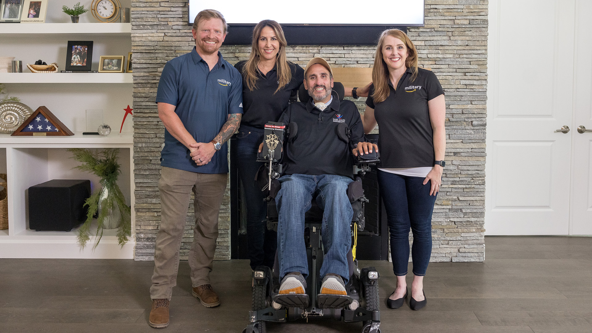 Matt and an Amazon colleague smile for a photo with Romy, and wounded veteran in a wheelchair, and his wife. 