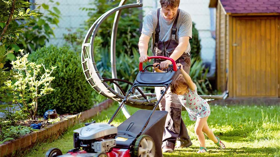 A father and daughter mow their lawn