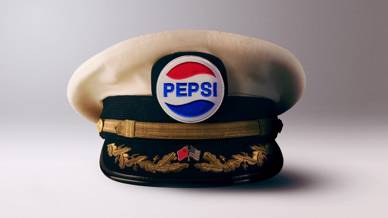 An illustration of a captain's hat with a 1980s era Pepsi logo and USSR and U.S. flag pins.