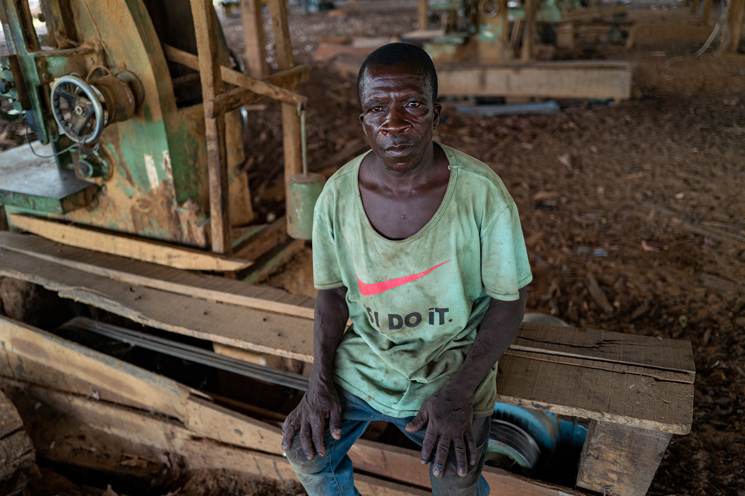 Mbaaba Kaper, an employee at an illegal timber trafficking warehouse in Yipala, Ghana, that was initially shut down in May 2019, sits on equipment in the warehouse on June 9.