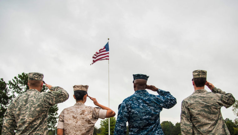 Service members saluting flag