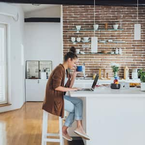 woman having coffee and using laptop in the kitchen