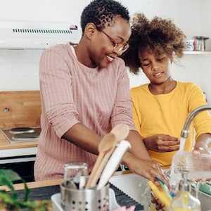 Girl helping mom wash the dishes at home