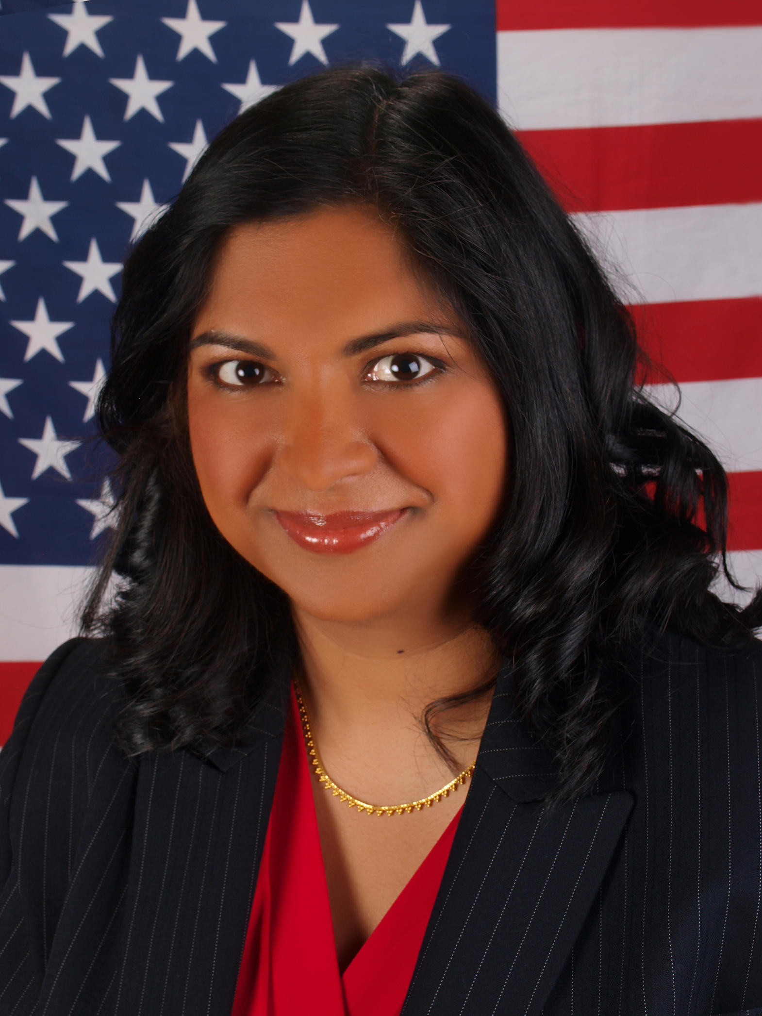 Woman stands in front of an American flag and smiles for a photo.