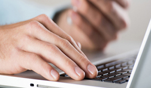 Person working on a laptop while accessing their smartphone.