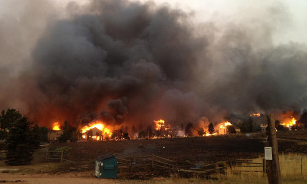 partially knocked down fence in the foreground, a wildfire in the background