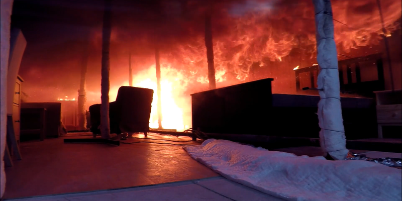 Flames roll on the ceiling of a darkened burning test room one minute before a flashover occurs.