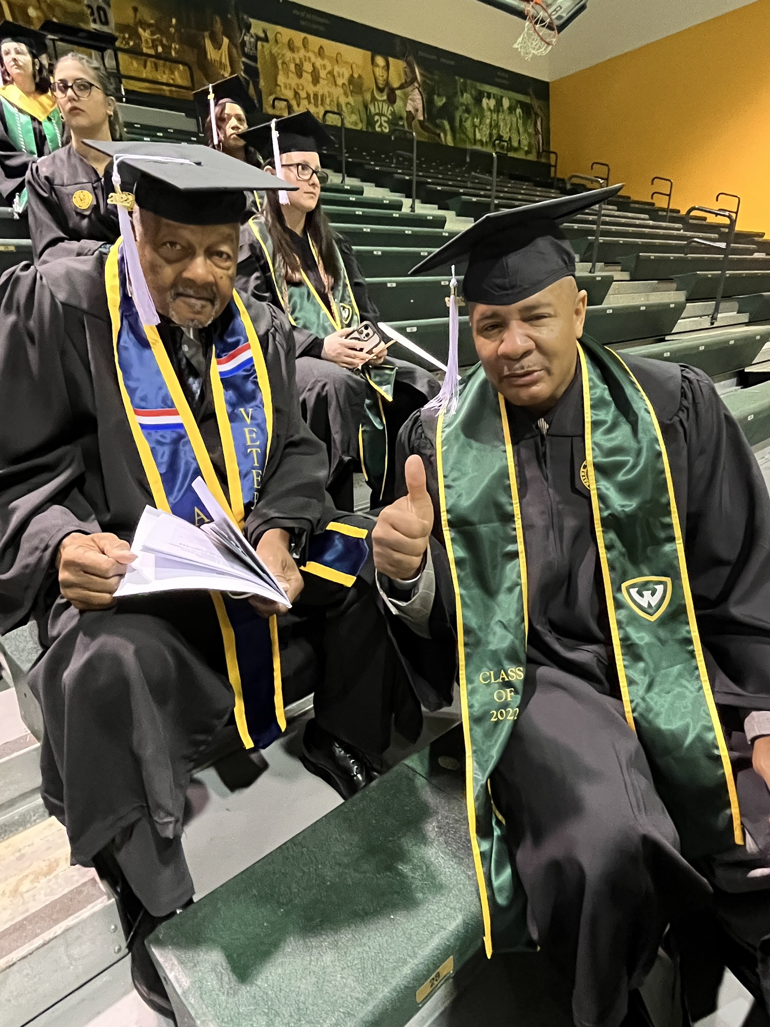 Two males in a black graduation cap and gown