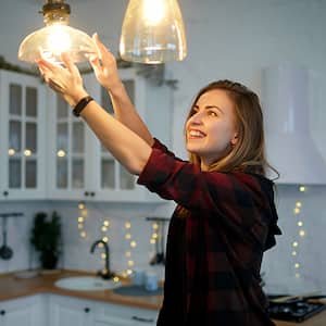 Woman screws in bulb on hanging light