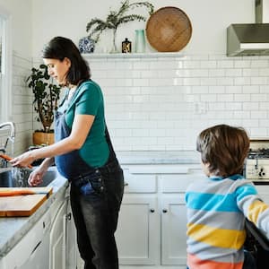 Pregnant mother washing vegetables at sink