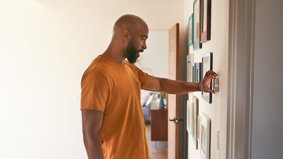 man adjusting temperature thermostat