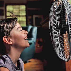 Boy smiling in front of fan