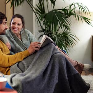 couple watching tv cuddled under blanket  