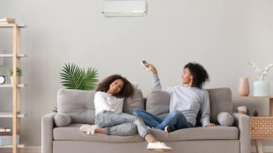 mother and daughter sit on couch in living room smiling and enjoying air conditioning