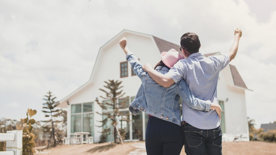 A couple celebrating in front of newly built house