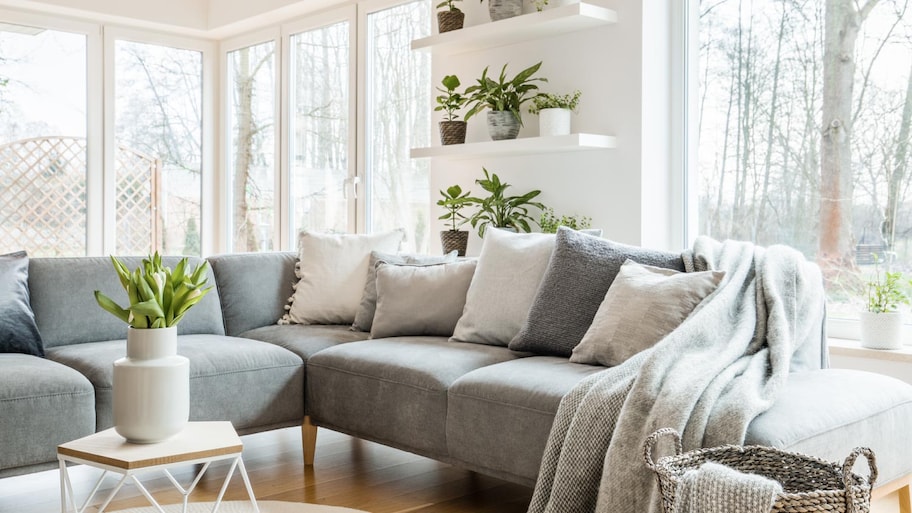 A grey corner couch with pillows and blankets
