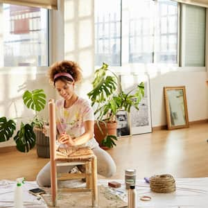 A woman painting a chair at home