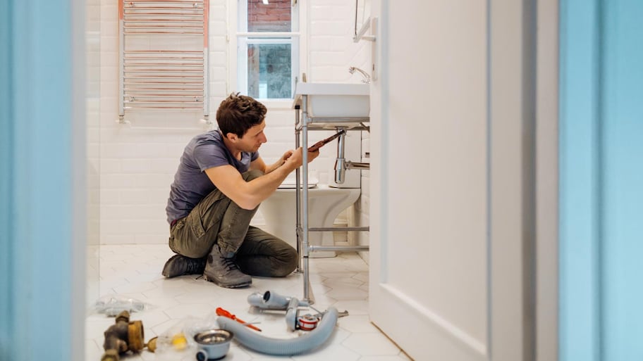 A plumber fixing a leak under the sink