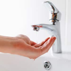 A woman’s hand under faucet with low pressure water stream