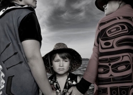 Two Native American adults hold hands in front of a child