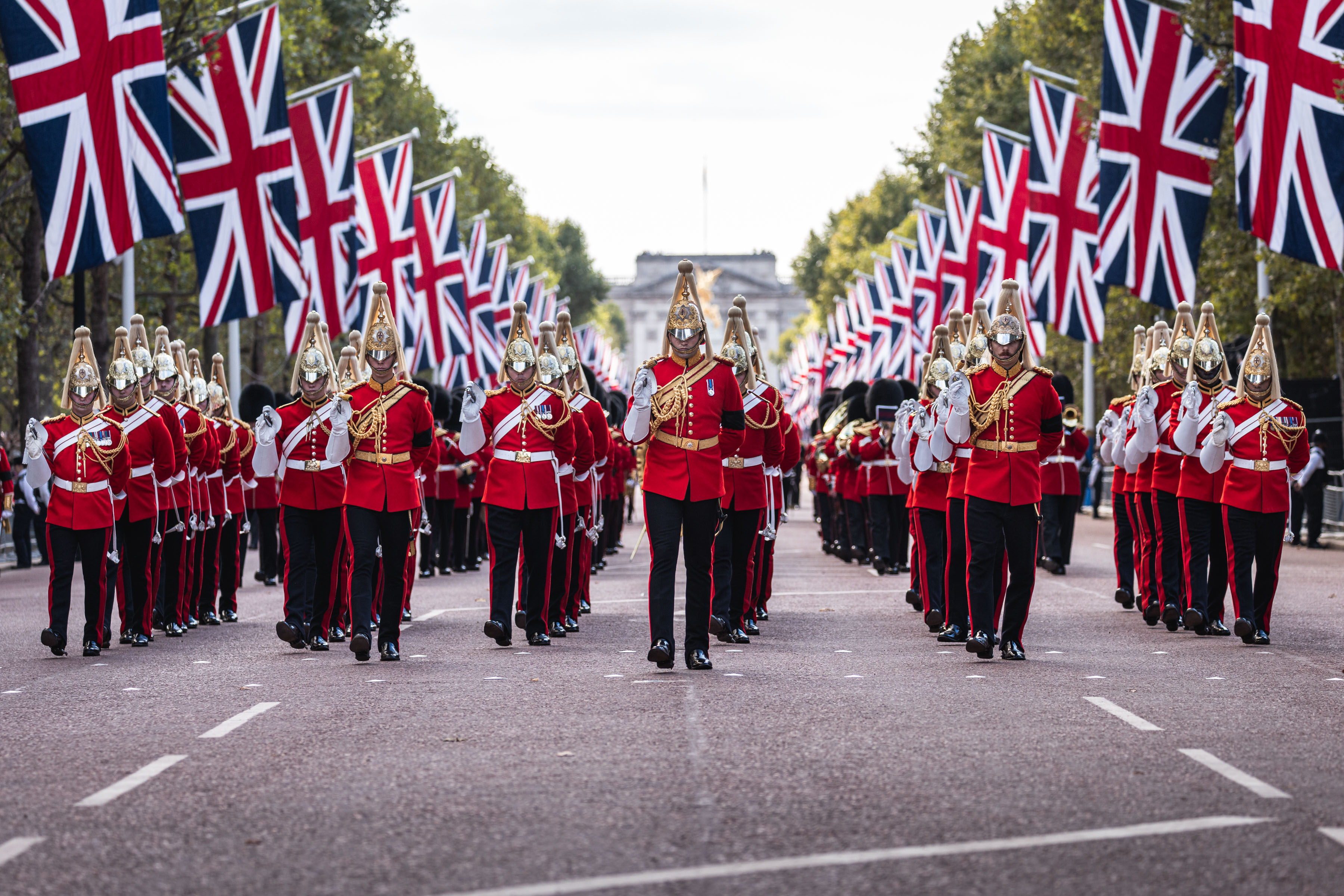 Members of the Household Calvary walk down Pall Mall with UK flags lining the street.