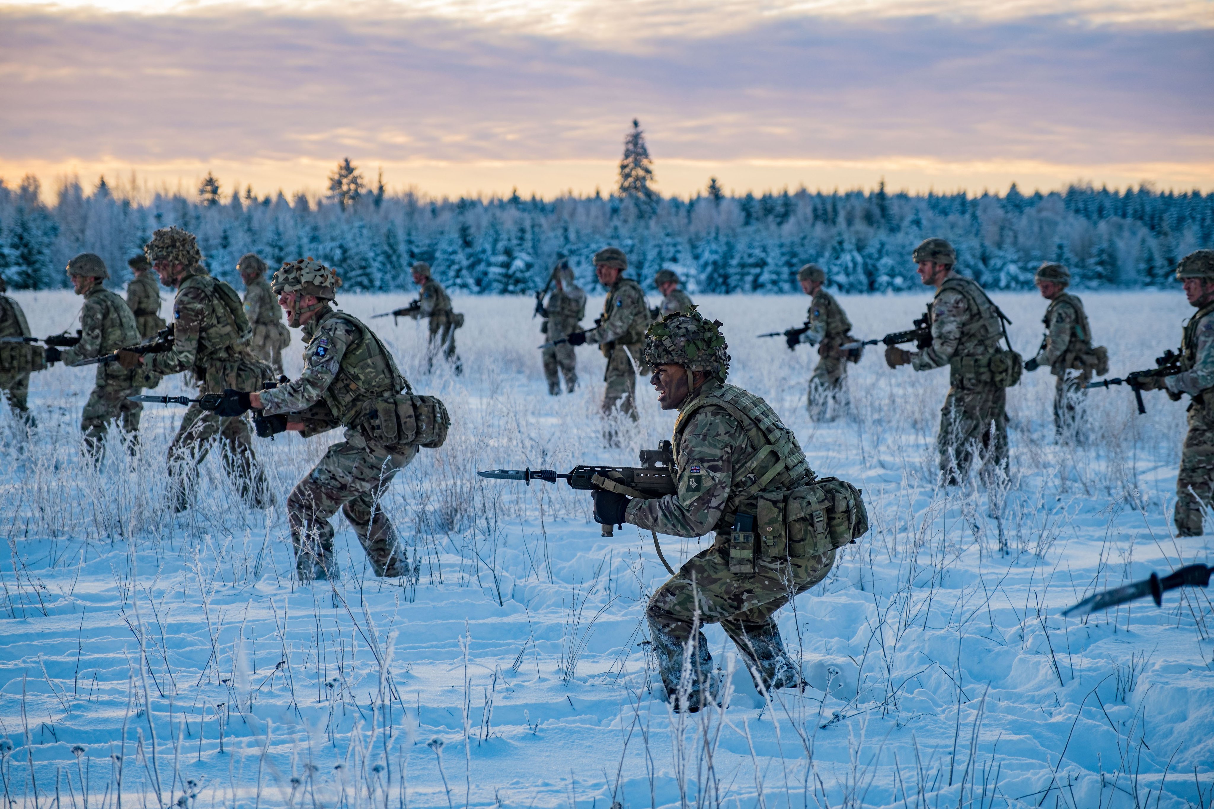 UK Armed Forces stand on guard in a snowy field as part of an exercise.