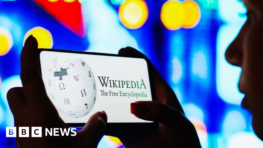 A woman looking at a phone reading wikipedia