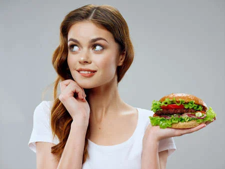 Woman in white t-shirt hamburger fast food diet food delicacy Фото со стока