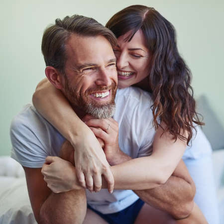 Im going to stay like this the whole day. a cheerful young couple embracing each other with a hug while relaxing on the bed at home during morning hours.