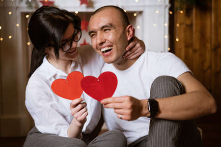 Happy young couple in love hold red heart in hand soft focus