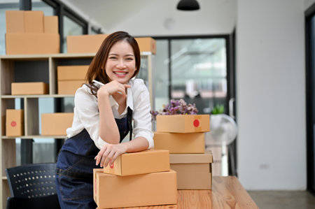 Charming and happy young asian female startup entrepreneur in her office stock room, smiling and looking at camera.