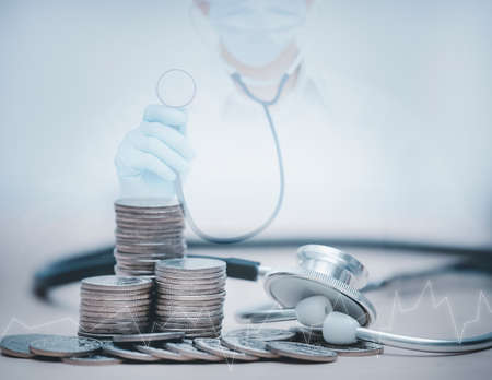 Stethoscope on coin stack on white background, stethoscope checking stack of money coins arranged as a graph on wooden table,saving and manage money for healthcare, life insurance business technology, Фото со стока