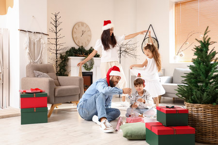 Happy family with cute little children celebrating christmas at home Фото со стока