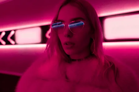 Pretty teen girl in stylish glasses and fur in pink neon lights sign on street wall, fashion trendy teenager hipster young woman retrowave synthwave purple style, modern glow night city background