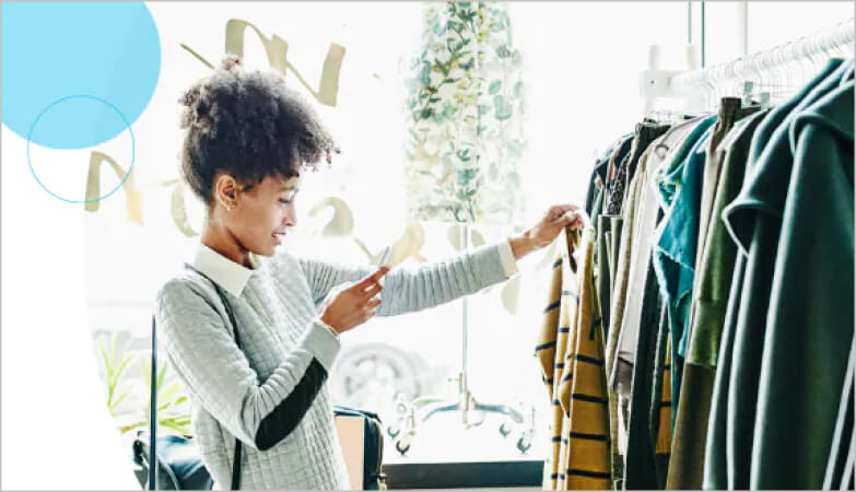 A person snaps a photo of a striped sweater at a retail location.