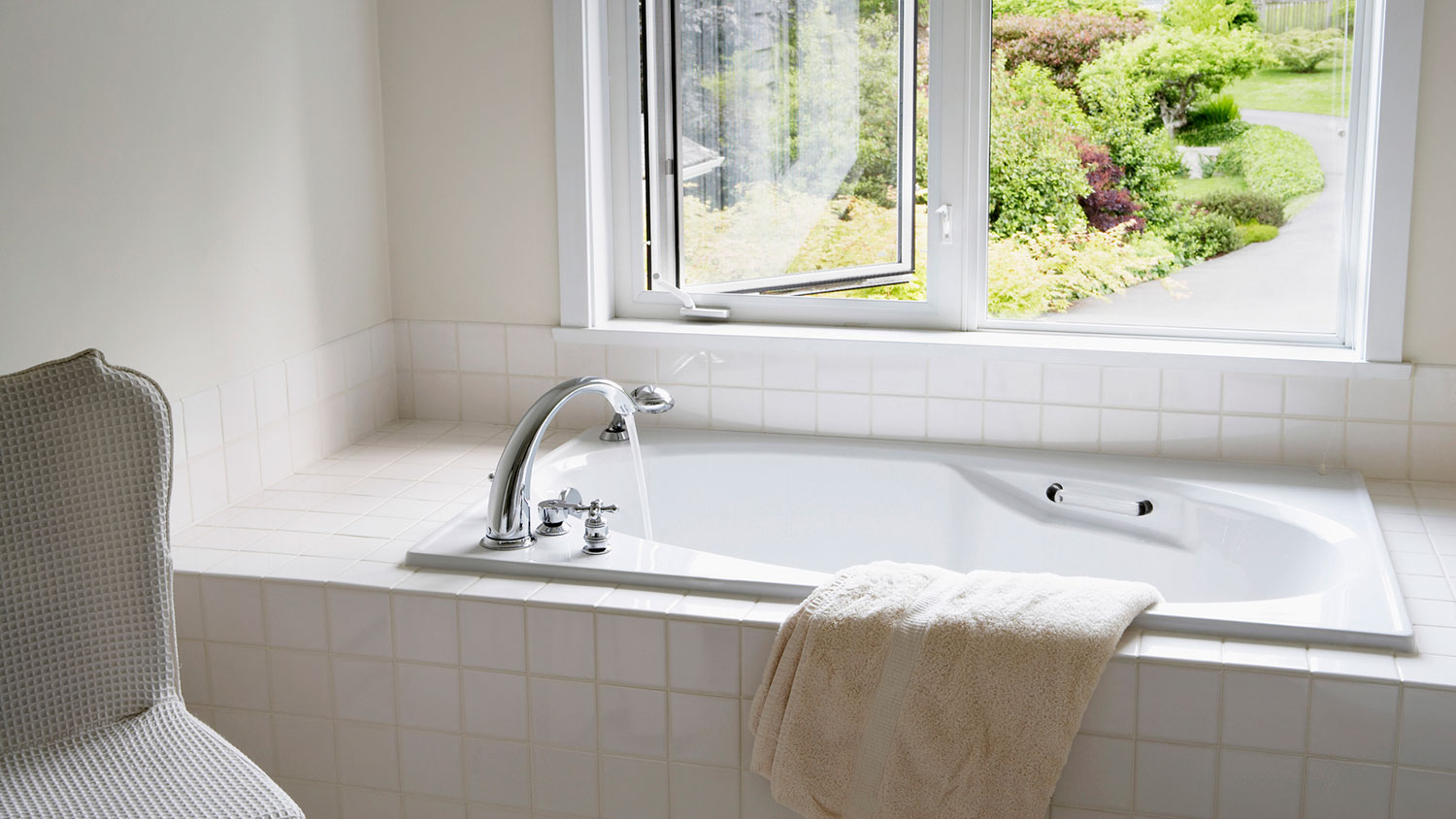 White tiled bathtub by an open window