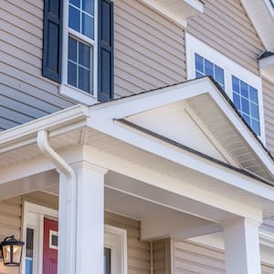 Portico leading to the entrance of vinyl horizontal lap siding covered building, with a roof structure over a walkway, supported by white rectangular columns on a single family home