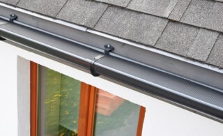 Plastic guard over new dark grey plastic rain gutter