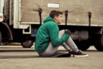 A Mid Adult Male Truck Driver Doing Exercises Before Road Trip by the side of a truck