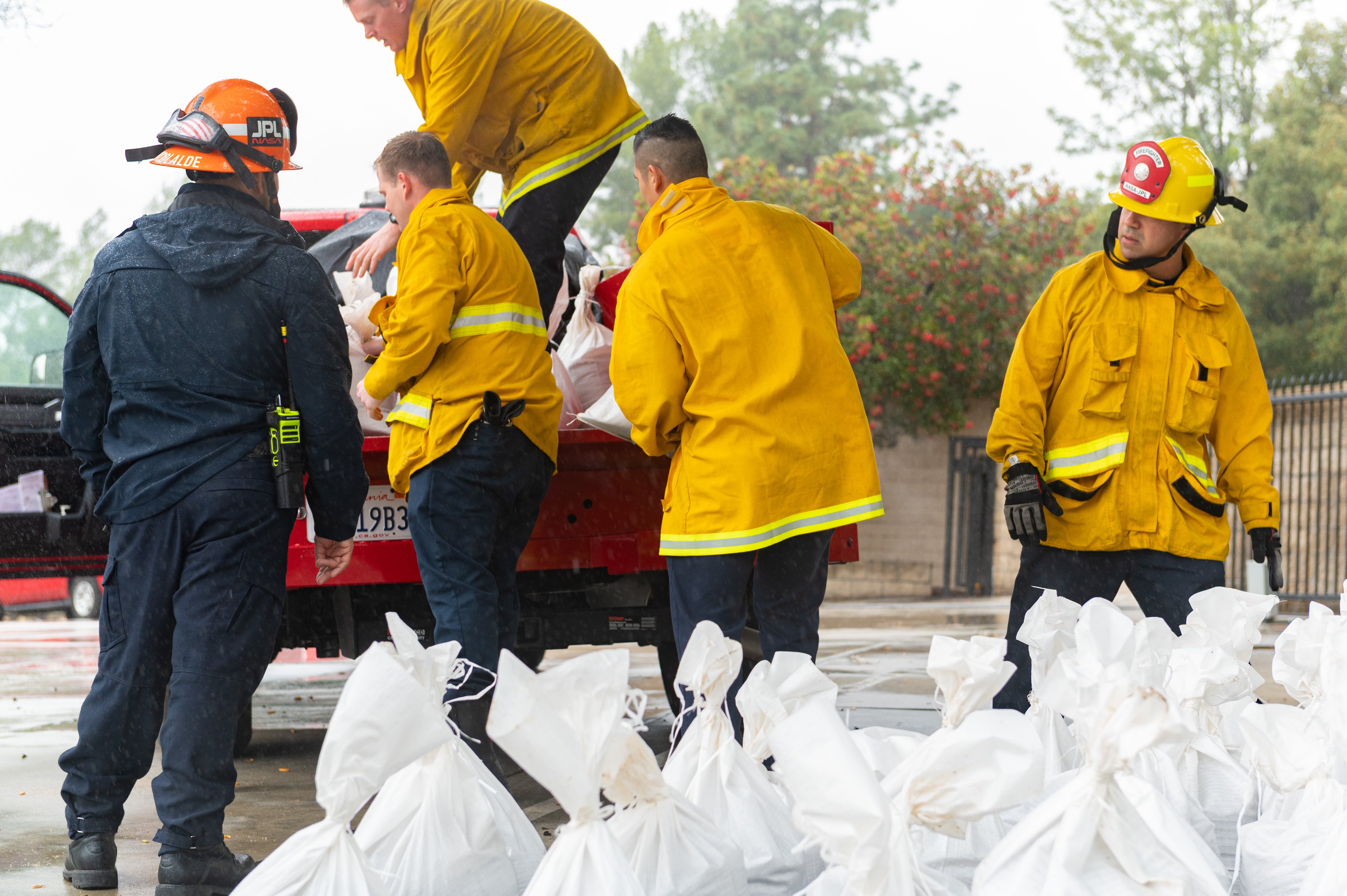 Firefighters load a truck with sandbags.