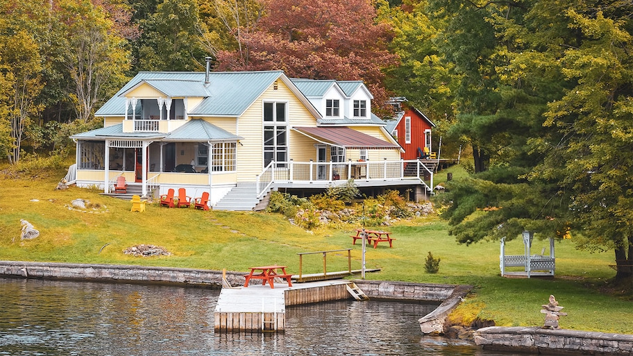 house by the water surrounded by trees in autumn 