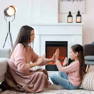 Mother and daughter sitting and playing clapping games in front of a fireplace 