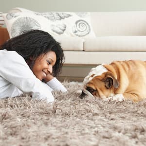 A woman lying on the carpet with her dog